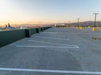 the empty parking lot at sunset with mountains in the background and many lines painted on it