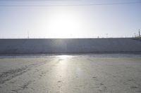 the sun is setting behind a large dam of water behind a wall on a highway