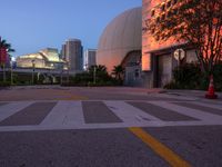 an empty intersection at sunset with city lights in the background and lights coming from buildings