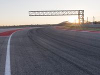 a person is riding a motorcycle down the track at sunset in a racetrack track with no running cars on it