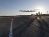 a person is riding a motorcycle down the track at sunset in a racetrack track with no running cars on it