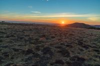 the sun is shining brightly on a sunset mountaintop with dry grass and scrubs