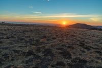 the sun is shining brightly on a sunset mountaintop with dry grass and scrubs