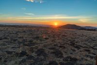 the sun is shining brightly on a sunset mountaintop with dry grass and scrubs