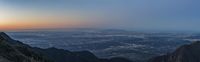 a sunset over the mountains and city below it, in california, near the ocean