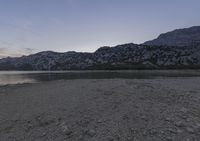 the sun sets at low tide and casts shadows on mountains in distance of the water