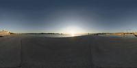 a panoramic view of the sun setting on the horizon in the water and sky