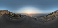 a long curved road is shown as the sun sets behind the ocean in a 360 - turn