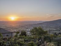 the sun is setting behind an orange orange sky above a city and hills in the background