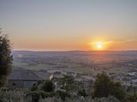 the sun is setting behind an orange orange sky above a city and hills in the background