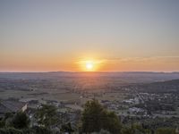 the sun is setting behind an orange orange sky above a city and hills in the background