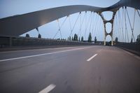 a long bridge that has lights on and pointing up at the right direction during sunset