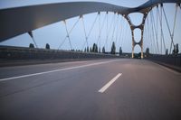 a long bridge that has lights on and pointing up at the right direction during sunset