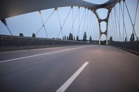 a long bridge that has lights on and pointing up at the right direction during sunset