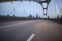 a long bridge that has lights on and pointing up at the right direction during sunset
