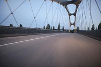 a long bridge that has lights on and pointing up at the right direction during sunset