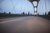 a long bridge that has lights on and pointing up at the right direction during sunset