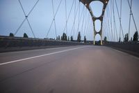 a long bridge that has lights on and pointing up at the right direction during sunset