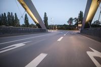 a long bridge that has lights on and pointing up at the right direction during sunset