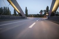 a long bridge that has lights on and pointing up at the right direction during sunset
