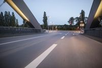 a long bridge that has lights on and pointing up at the right direction during sunset