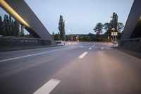 a long bridge that has lights on and pointing up at the right direction during sunset