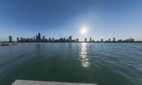 the sun is setting over the lake in front of the city skyline with the sea and beach