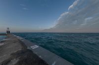 sunsets on the ocean over a pier and a blue ocean and pink clouds in the distance