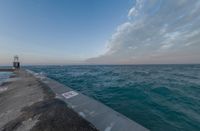 sunsets on the ocean over a pier and a blue ocean and pink clouds in the distance