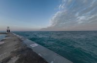 sunsets on the ocean over a pier and a blue ocean and pink clouds in the distance