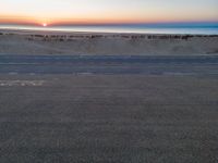 an aerial view of the sunset over a road on the beach and a beach line