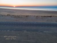 an aerial view of the sunset over a road on the beach and a beach line