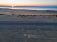 an aerial view of the sunset over a road on the beach and a beach line