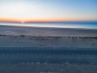 an aerial view of the sunset over a road on the beach and a beach line