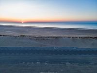 an aerial view of the sunset over a road on the beach and a beach line