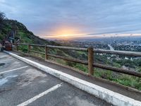 a view over a fenced parking lot in the mountains, at sunset with the sun setting