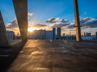 sunset over rooftop parking garage with cityscape in background and large window with cloudy sky in foreground