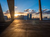 sunset over rooftop parking garage with cityscape in background and large window with cloudy sky in foreground