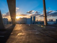 sunset over rooftop parking garage with cityscape in background and large window with cloudy sky in foreground