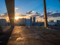 sunset over rooftop parking garage with cityscape in background and large window with cloudy sky in foreground