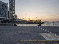 a parking lot in front of a body of water at sunset with boats on it