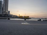 a parking lot in front of a body of water at sunset with boats on it