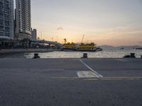 a parking lot in front of a body of water at sunset with boats on it