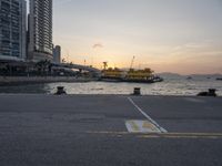 a parking lot in front of a body of water at sunset with boats on it