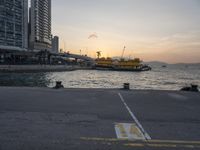 a parking lot in front of a body of water at sunset with boats on it