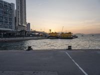 a parking lot in front of a body of water at sunset with boats on it