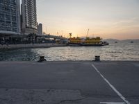 a parking lot in front of a body of water at sunset with boats on it