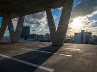 the sun is setting over a parking lot with modern buildings in the background, with low shadows