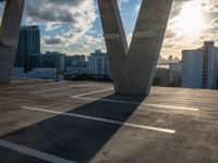 the sun is setting over a parking lot with modern buildings in the background, with low shadows