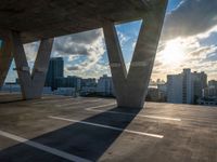 the sun is setting over a parking lot with modern buildings in the background, with low shadows